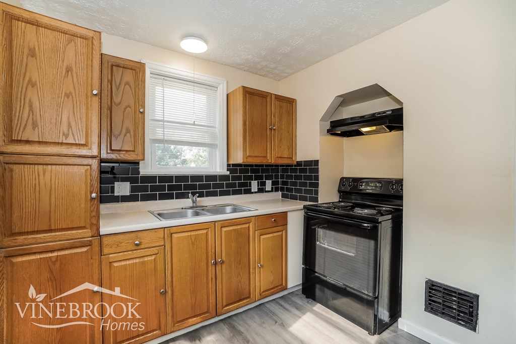 a kitchen with black appliances and wooden cabinets and a sink