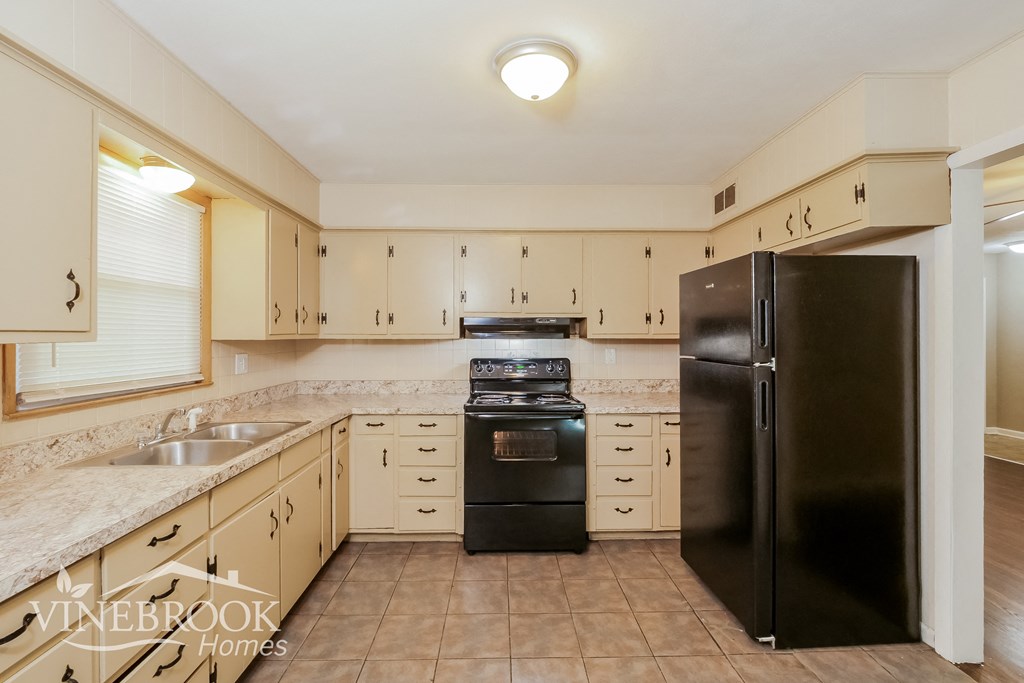 a kitchen with white cabinets and black appliances and a black refrigerator