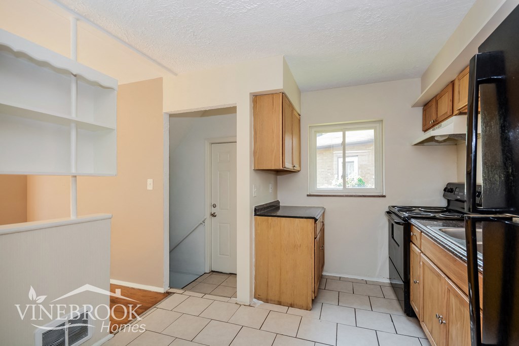 a kitchen with black appliances and wooden cabinets and a window
