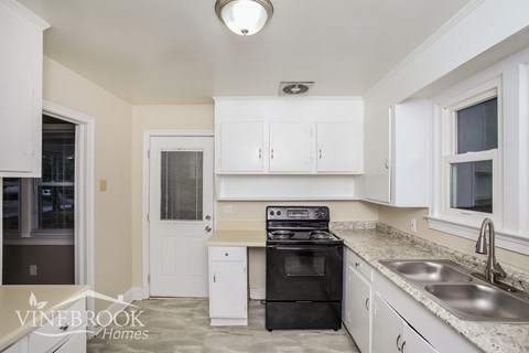 A kitchen with white cabinets and a black oven.