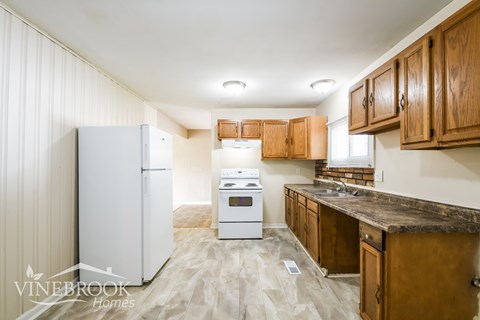 A kitchen with a white refrigerator and wooden cabinets.
