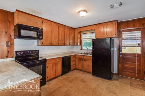 a kitchen with wooden cabinets and black appliances