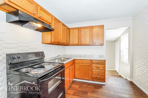 A kitchen with wooden cabinets and a black stove top oven.
