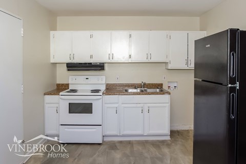 A kitchen with white cabinets and a black refrigerator.