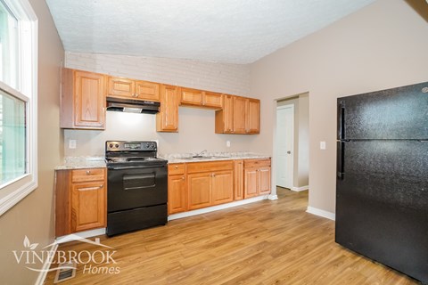 A kitchen with wooden cabinets and a black refrigerator.