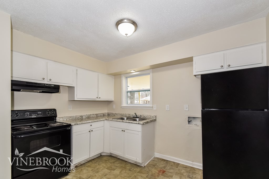 A kitchen with white cabinets and a black stove top oven.
