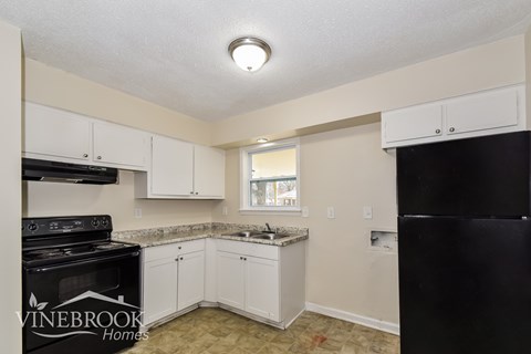 A kitchen with white cabinets and a black stove top oven.