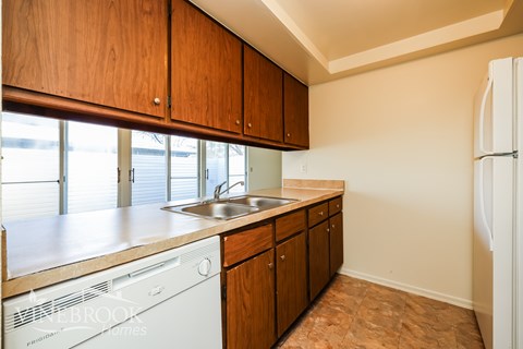 A kitchen with wooden cabinets and a white dishwasher.