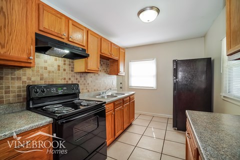 A kitchen with wooden cabinets and a black stove top oven.