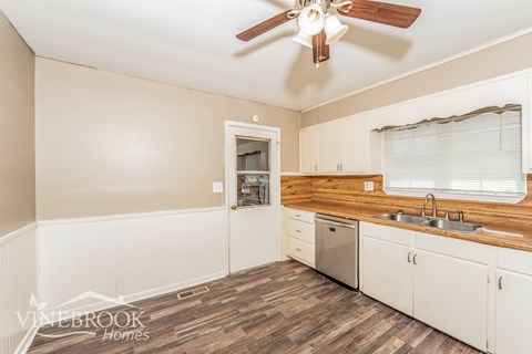A kitchen with a wood counter top and white cabinets.