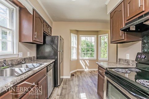 A kitchen with wooden cabinets and a black refrigerator.