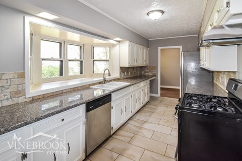 A kitchen with a black stove top oven and white cabinets.