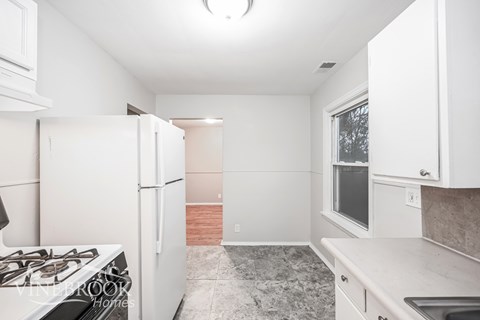 A kitchen with white cabinets and a tiled floor.