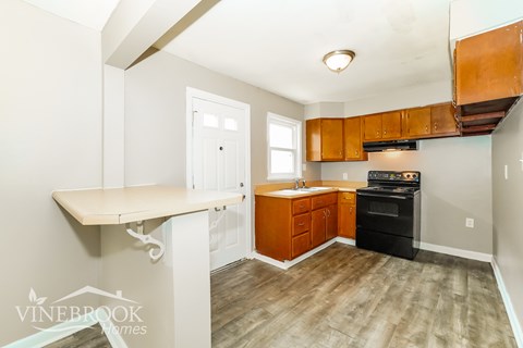 A kitchen with a black oven and wooden cabinets.