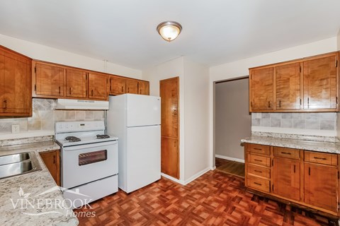 A kitchen with wooden cabinets and a white refrigerator.