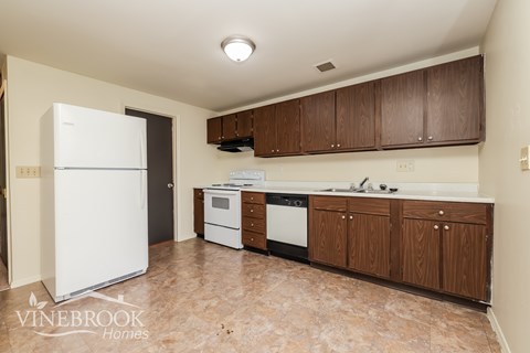 A kitchen with a white fridge and brown cabinets.
