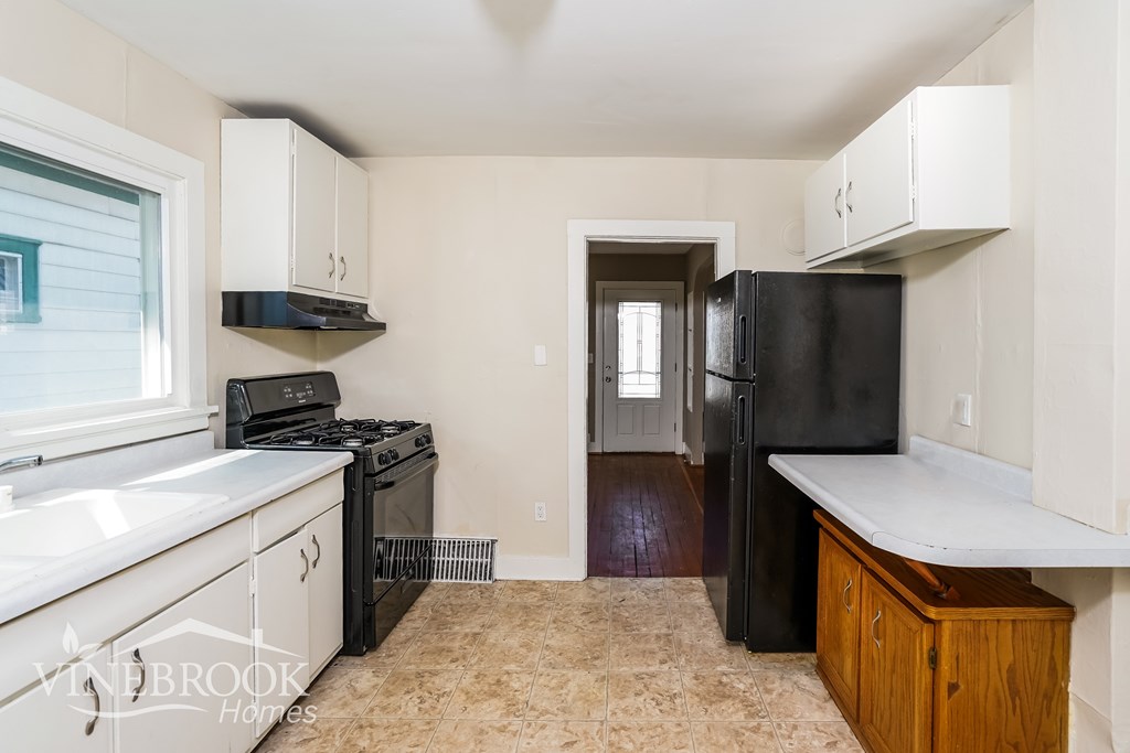 A kitchen with a black refrigerator and a stove top oven.