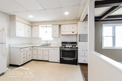 A white kitchen with a black oven and a window.