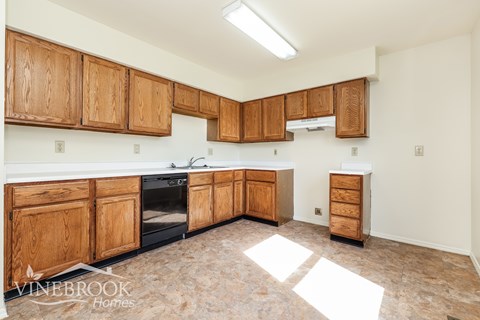 A kitchen with wooden cabinets and a tiled floor.