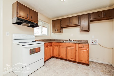 A kitchen with a white stove and wooden cabinets.