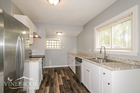 A kitchen with a refrigerator, sink, and cabinets.