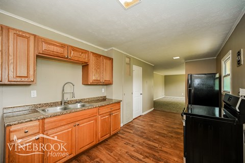 A kitchen with wooden cabinets and a black fridge.