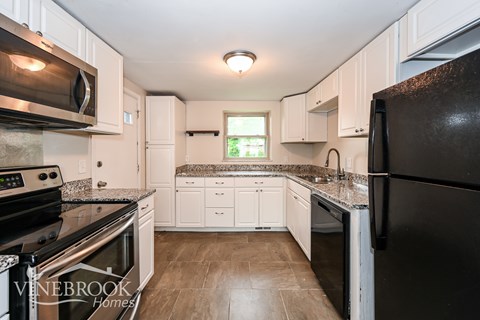 A kitchen with black appliances and white cabinets.