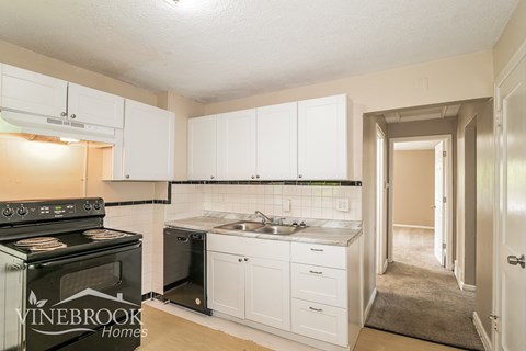 A kitchen with white cabinets and a black stove top oven.