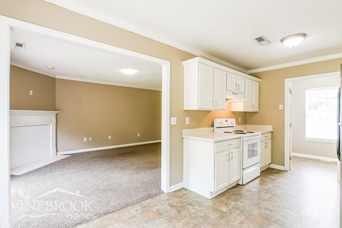 A kitchen with white cabinets and appliances in a room with tan walls.