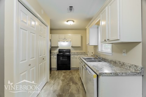 A kitchen with granite countertops and white cabinets.