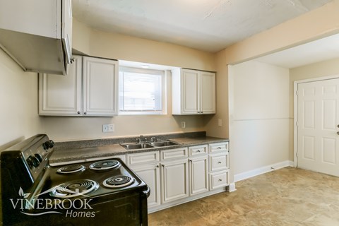 A kitchen with a black stove top oven and white cabinets.