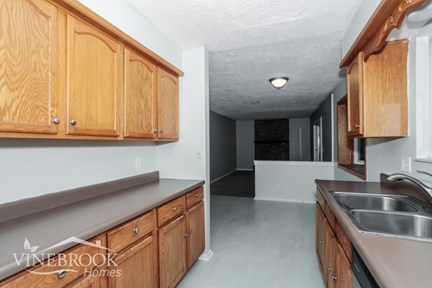A kitchen with wooden cabinets and a Vinebrook Homes logo.