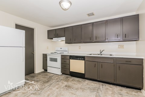A kitchen with a white refrigerator and brown cabinets.