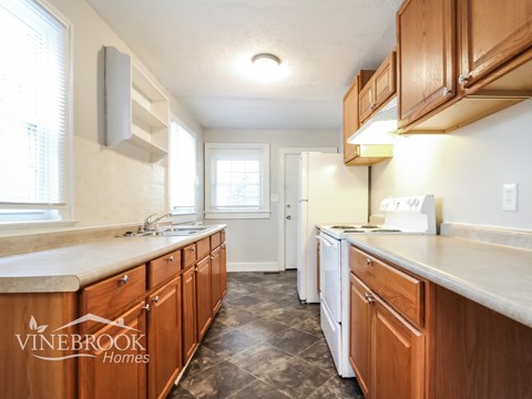 A kitchen with wooden cabinets and a Vinebrook Homes logo.