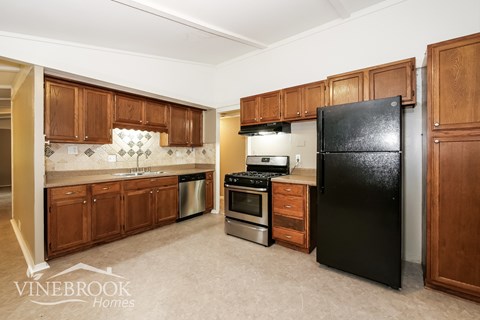 A kitchen with wooden cabinets and a black refrigerator.