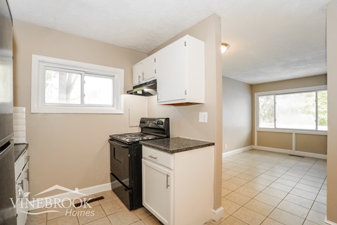 A kitchen with a black stove top oven and white cabinets.