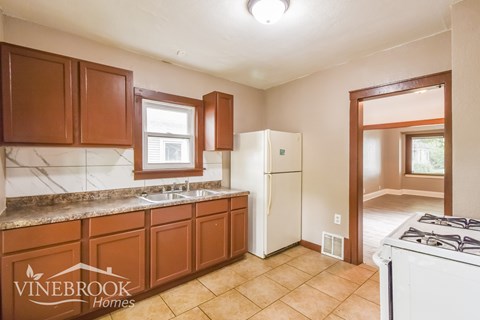 A kitchen with brown cabinets and a white fridge.