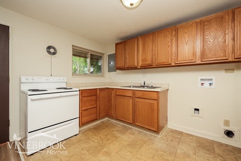 A kitchen with wooden cabinets and a white stove top oven.