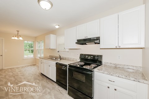 A kitchen with a black stove top oven and white cabinets.