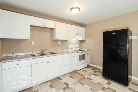 A kitchen with white cabinets and a black refrigerator.
