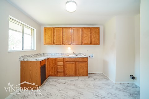 A kitchen with wooden cabinets and a marble countertop.