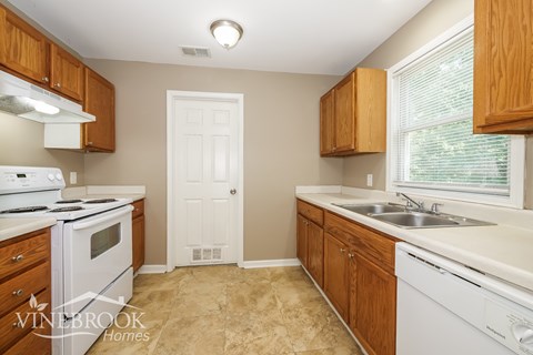 A kitchen with wooden cabinets and a white stove top oven.