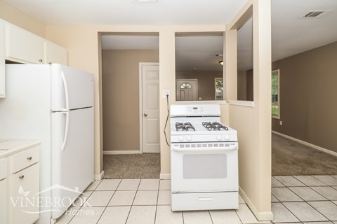 A white fridge and stove in a kitchen with beige walls.