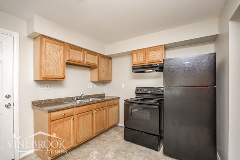 A kitchen with wooden cabinets and black appliances.