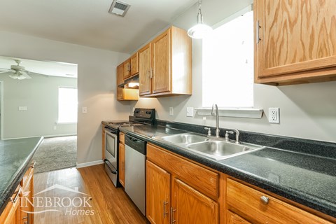 A kitchen with wooden cabinets and a black countertop.