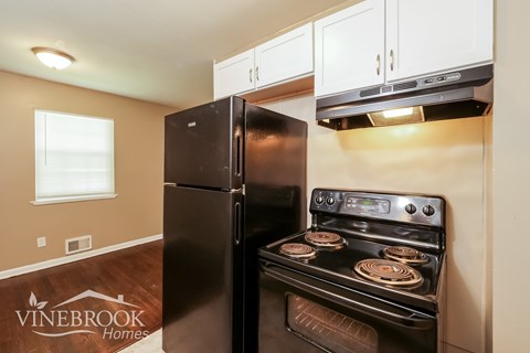 A black refrigerator and stove in a kitchen with a Vinebrook Homes logo on the floor.