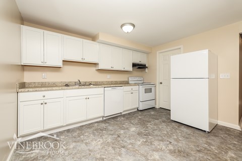 A kitchen with white cabinets and appliances is available for rent.