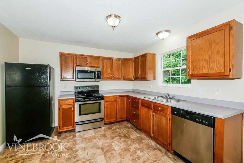 A kitchen with wooden cabinets and a black fridge.