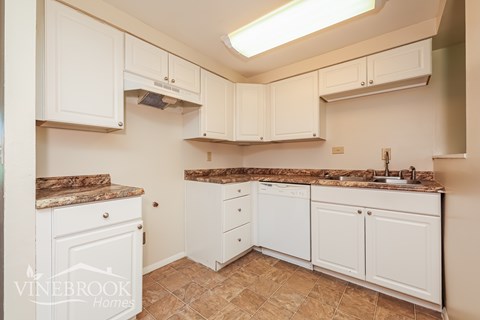 A kitchen with white cabinets and a granite countertop.