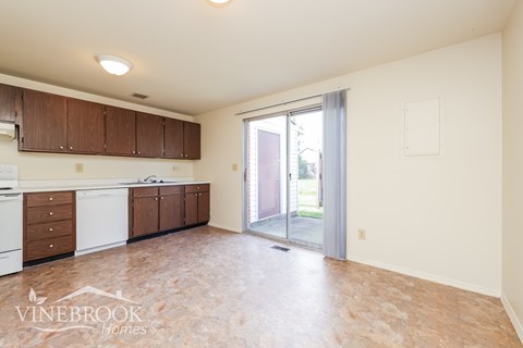 A kitchen with wooden cabinets and a tiled floor.